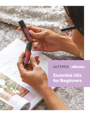 doterra free ebook essential oils for beginners woman holding two essential oil roll on bottles over open book